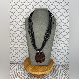 Elegant glass bead necklace with mother-of-pearl charm in black and brown.